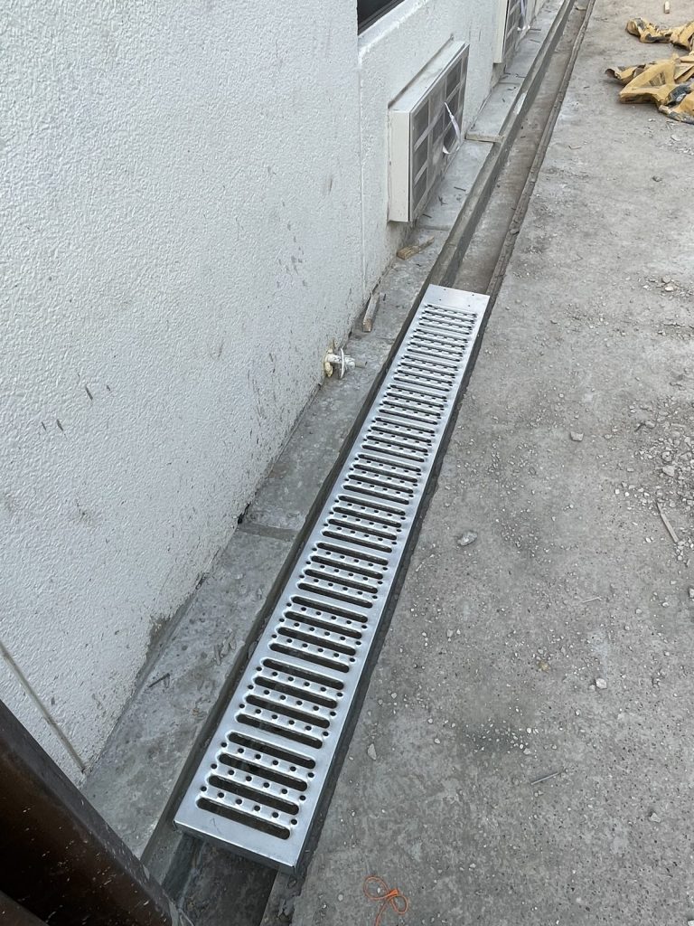 Recent Landscaping Projects In Austin, Tx 7 channel drain installed along a house wall to move water away from the foundation