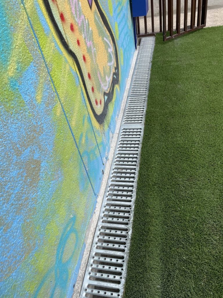 Recent Landscaping Projects In Austin, Tx 10 artificial turf edge with a channel drain along the mural wall