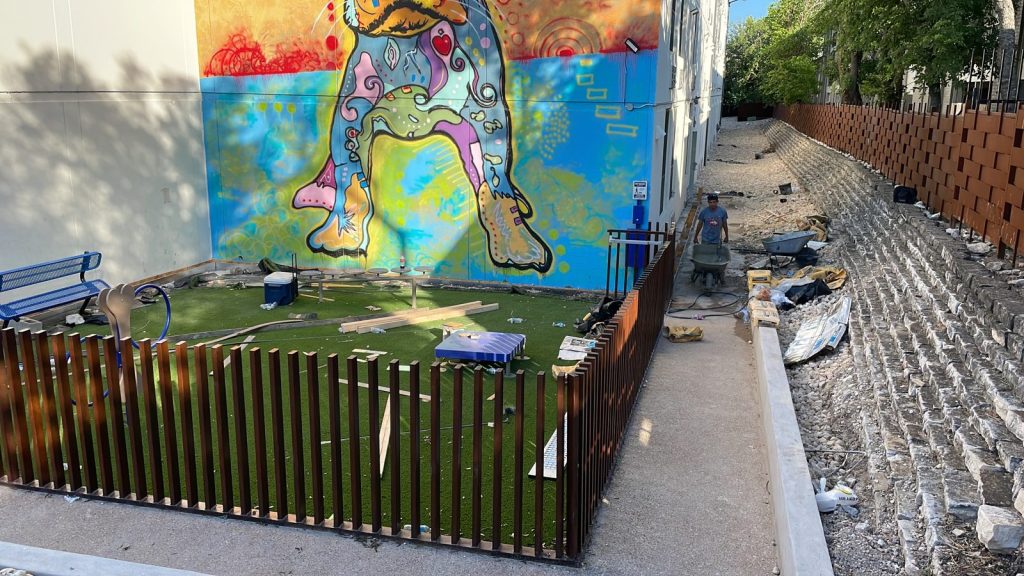 Recent Landscaping Projects In Austin, Tx 9 artificial turf play area with low wood fence next to a mural, austin tx